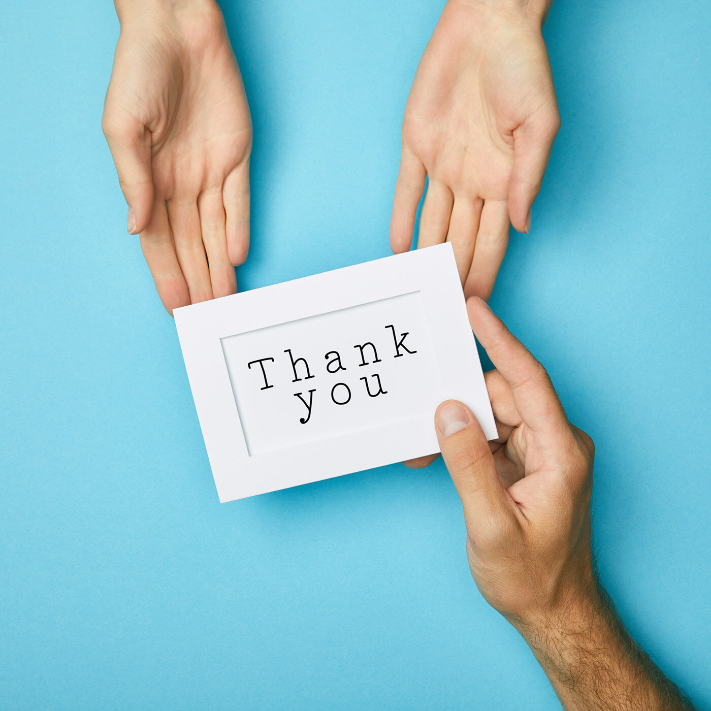 cropped view of man giving white card in frame with thank you lettering to woman on blue background